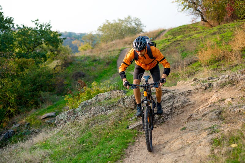 Cyklist i apelsin som rider mountainbiket på Autumn Rocky Trail Extrem sport och Enduro som cyklar begrepp royaltyfri foto Cyklist i apelsin som rider mountainbiket på Autumn Rocky Trail Extrem sport och Enduro som cyklar begrepp royaltyfri foto
