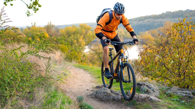 Cyklista w Pomarańczowej jazdie rower górski na jesień Skalistym śladzie Krańcowy sport i Enduro Jechać na rowerze pojęcie obrazy stock Cyklista w Pomarańczowej jazdie rower górski na jesień Skalistym śladzie Krańcowy sport i Enduro Jechać na rowerze pojęcie obrazy stock