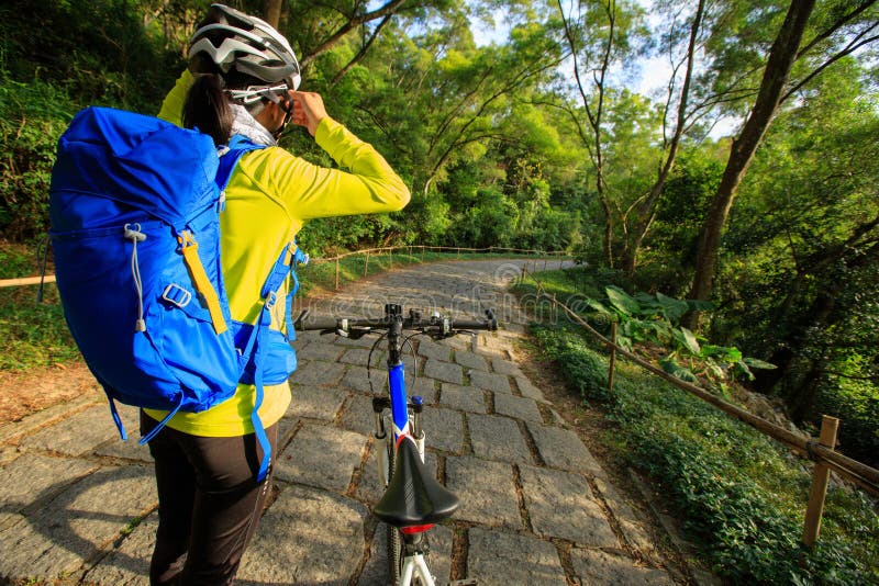 Cyklisten justerar hjälmbältet, innan han rider mountainbiket på skogslinga royaltyfria foton Cyklisten justerar hjälmbältet, innan han rider mountainbiket på skogslinga royaltyfria foton