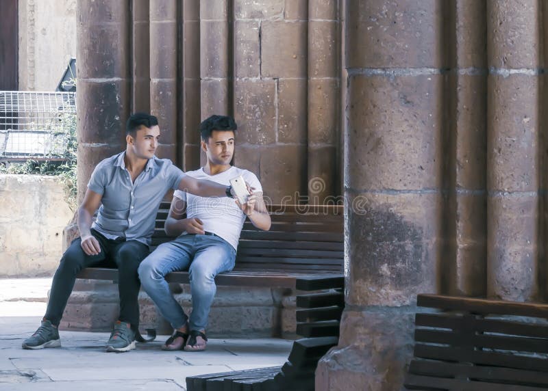 CYPRUS, NICOSIA - JUNE 10, 2019: Two male sitting and talking together on a bench near the ancient columns of the historic