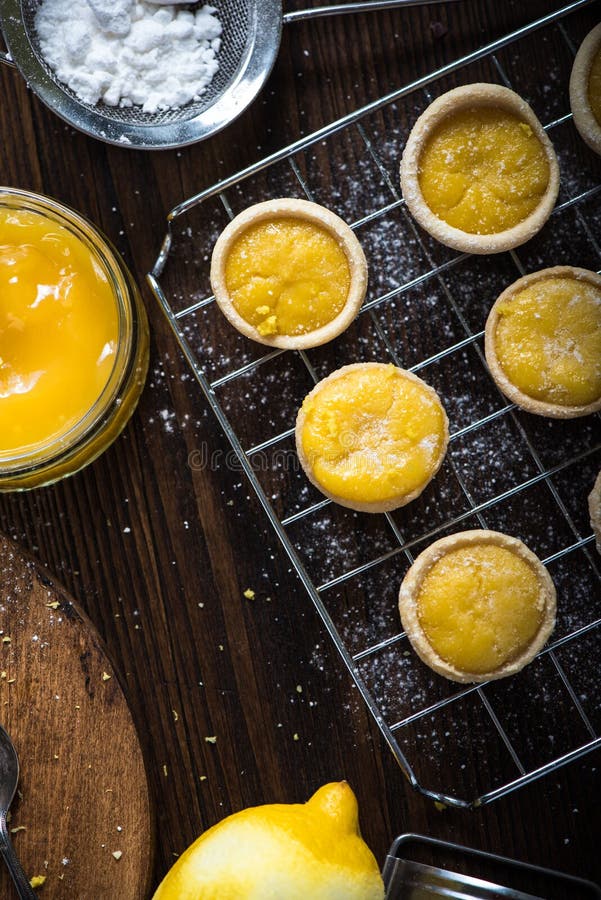 Lemon and custard tarts on cooling tray on wooden rustic table. Lemon and custard tarts on cooling tray on wooden rustic table