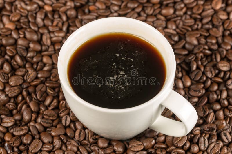 Czarna kawa w filiżanki pozyci na kawowych fasolach w topview obraz stock Czarna kawa w filiżanki pozyci na kawowych fasolach w topview obraz stock