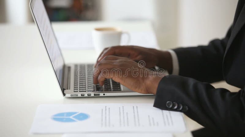Czarna samiec wręcza pisać na maszynie na laptop klawiaturze przy biurowym biurkiem