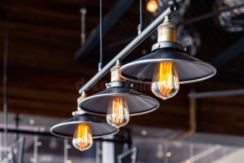 Black iron loft chandeliers with edison lamps on a black background, bokeh. Concept of modern interior design of a restaurant, cafe, apartment, office, shop, wine bar. Black iron loft chandeliers with edison lamps on a black background, bokeh. Concept of modern interior design of a restaurant, cafe, apartment, office, shop, wine bar