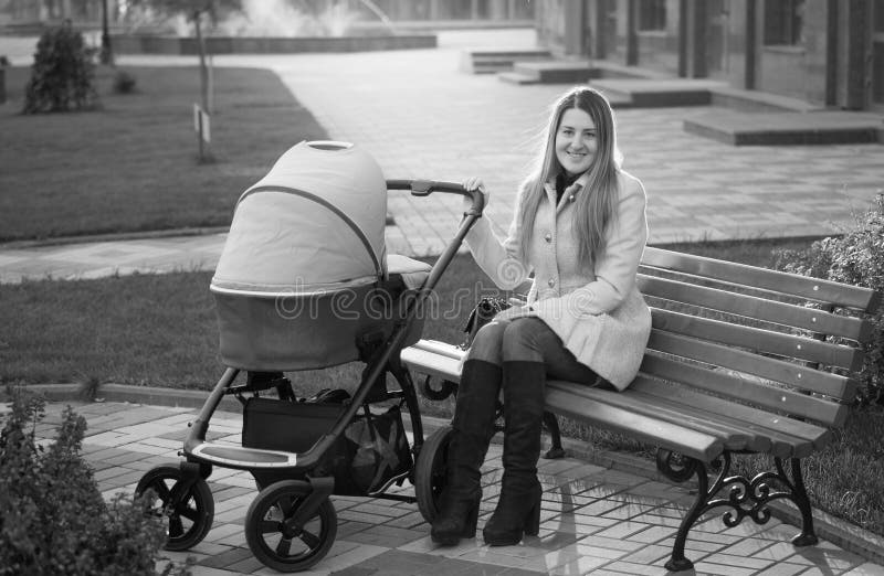 Czarny i biały fotografia macierzysty obsiadanie na ławce z dziecka strol obrazy stock Czarny i biały fotografia macierzysty obsiadanie na ławce z dziecka strol obrazy stock