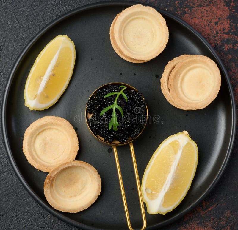 Czarny jesiotr kawior w miedzianych klinach cytrynowych i pustych klockach w czarnej blacie. Czarny kawior jesienny w miedzianych klinach cytrynowych i pustych tartletach w czarnym widoku.