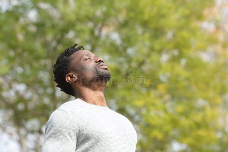 Czarny poważny mężczyzna oddychający świeżym powietrzem w parku