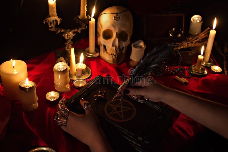 Czarownica trzyma książkę z pentagramem, czaszką i świeczkami, obraz stock Czarownica trzyma książkę z pentagramem, czaszką i świeczkami, obraz stock