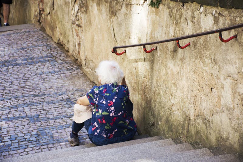 Czechia old women sitting lonely at pathway of Prague castle