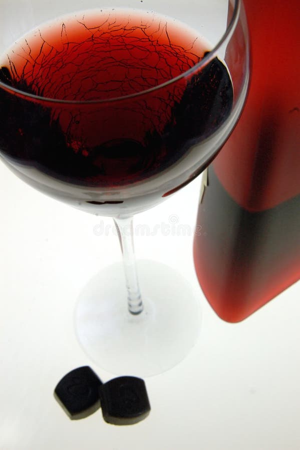 A glass of red wine and two dark chocolates on white background. A glass of red wine and two dark chocolates on white background