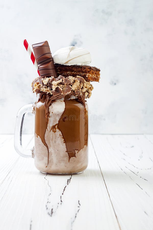 Czekoladowy ulegający exreme milkshake z tortem, marshmallow i cukierkami punktu, Szalonego freakshake karmowy trend obraz stock Czekoladowy ulegający exreme milkshake z tortem, marshmallow i cukierkami punktu, Szalonego freakshake karmowy trend obraz stock