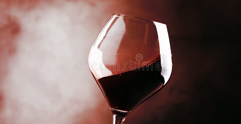 Red wine, splash in a glass, dry cabernet sauvignon, dark red background, defocused in motion image, shallow depth of field. Red wine, splash in a glass, dry cabernet sauvignon, dark red background, defocused in motion image, shallow depth of field