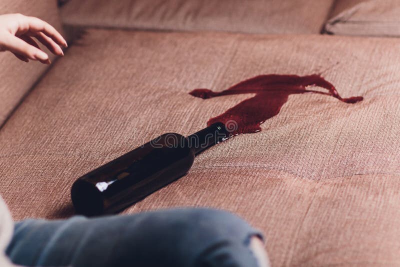 Red wine spilled on a brown couch sofa dark bottle of red wine dropped. Red wine spilled on a brown couch sofa dark bottle of red wine dropped.