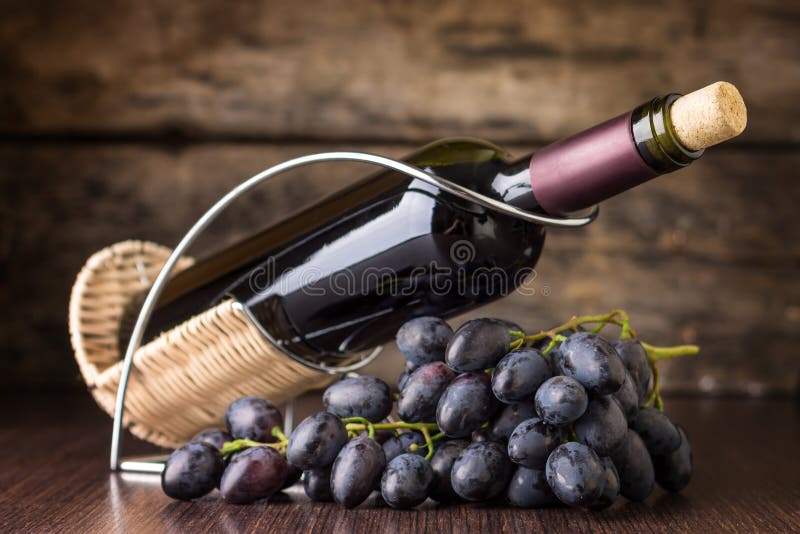 Red wine with claster of dark blue grapes at wooden table. Winery still-life on wood background. Red wine with claster of dark blue grapes at wooden table. Winery still-life on wood background