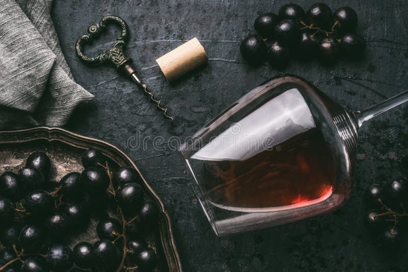 Red wine concept with glass, grapes and vintage corkscrew on dark background, top view. Red wine concept with glass, grapes and vintage corkscrew on dark background, top view