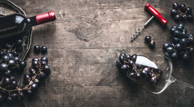 Red wine background with bottle and corkscrew , grapes and wine glass on dark vintage wooden, top view, frame. Red wine background with bottle and corkscrew , grapes and wine glass on dark vintage wooden, top view, frame