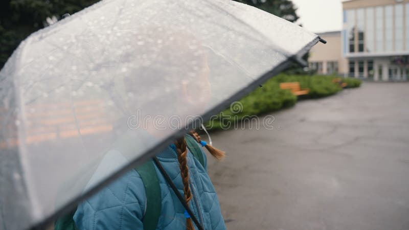 Czerwonowłosa dziewczynka stojąca przezroczysta parasolka uśmiechająca się obraca się wokół miasta deszczowego poza parkiem spacer