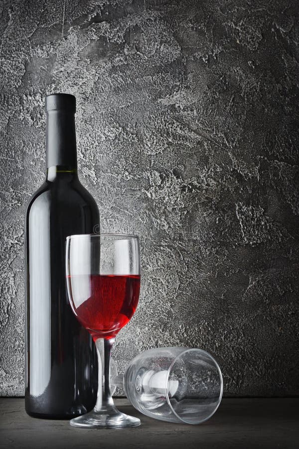 Red wine bottle and glasses for tasting in cellar on dark gray concrete background. Red wine bottle and glasses for tasting in cellar on dark gray concrete background