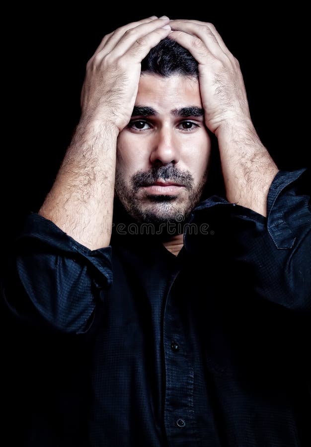 Young hispanic man suffering a headache or a very strong stress or depression isolated on black. Young hispanic man suffering a headache or a very strong stress or depression isolated on black