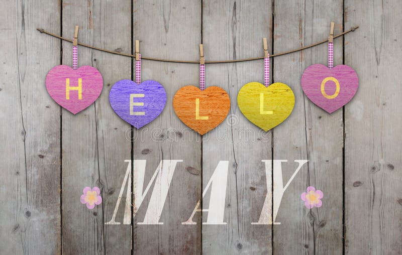 Hello May written on hanging pink and orange and purple hearts and weathered wooden background, with flowers. Hello May written on hanging pink and orange and purple hearts and weathered wooden background, with flowers