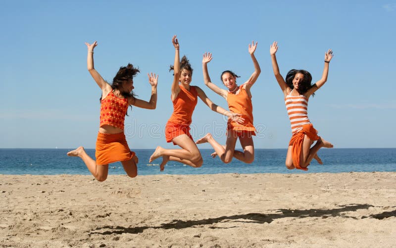 Four girls in orange clothes jumping on the beach. Four girls in orange clothes jumping on the beach