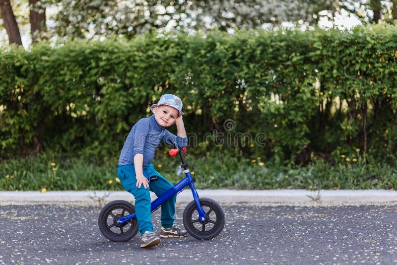 Czteroletnia u?miechni?ta ch?opiec w kapeluszu siedzi na b??kitnym bieg rowerze Bicykl bez nast?p?w obrazy royalty free Czteroletnia u?miechni?ta ch?opiec w kapeluszu siedzi na b??kitnym bieg rowerze Bicykl bez nast?p?w obrazy royalty free