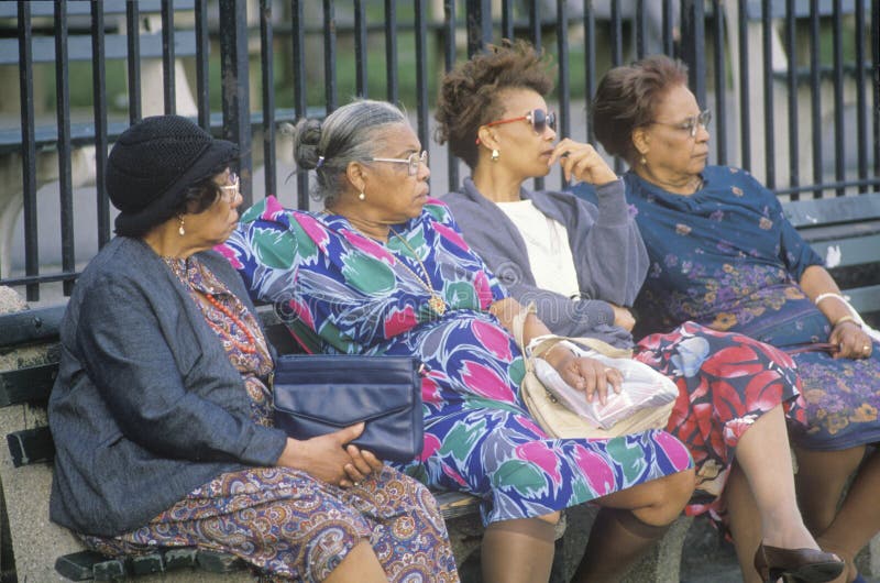 Four African-American women sitting on a park bench. Four African-American women sitting on a park bench