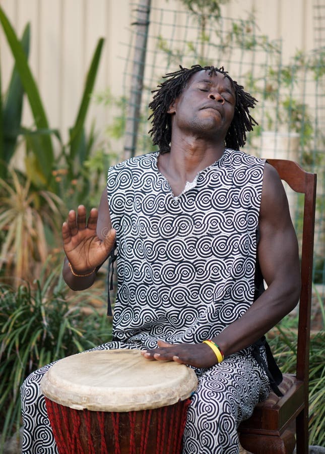 African Drummer playing the djembe, feeling happiness and thoroughly enjoying the rhythm of the music. African Drummer playing the djembe, feeling happiness and thoroughly enjoying the rhythm of the music