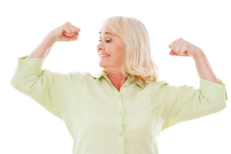 Cheerful senior woman checking her biceps and smiling while standing isolated on white background. Cheerful senior woman checking her biceps and smiling while standing isolated on white background