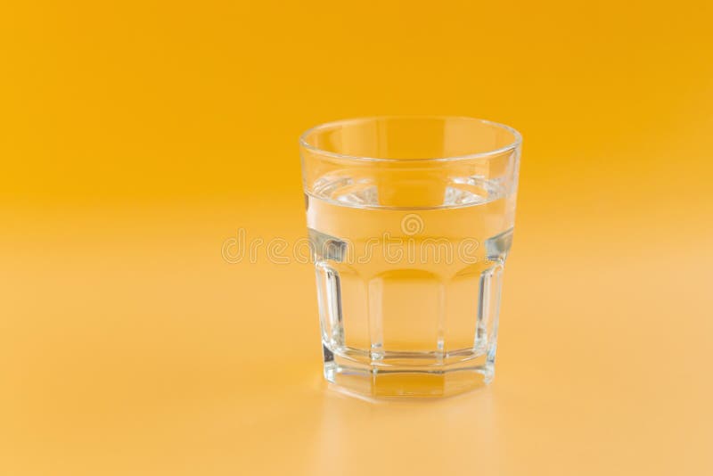Czysta woda w szkle na pomarańczowym tle obraz stock Czysta woda w szkle na pomarańczowym tle obraz stock