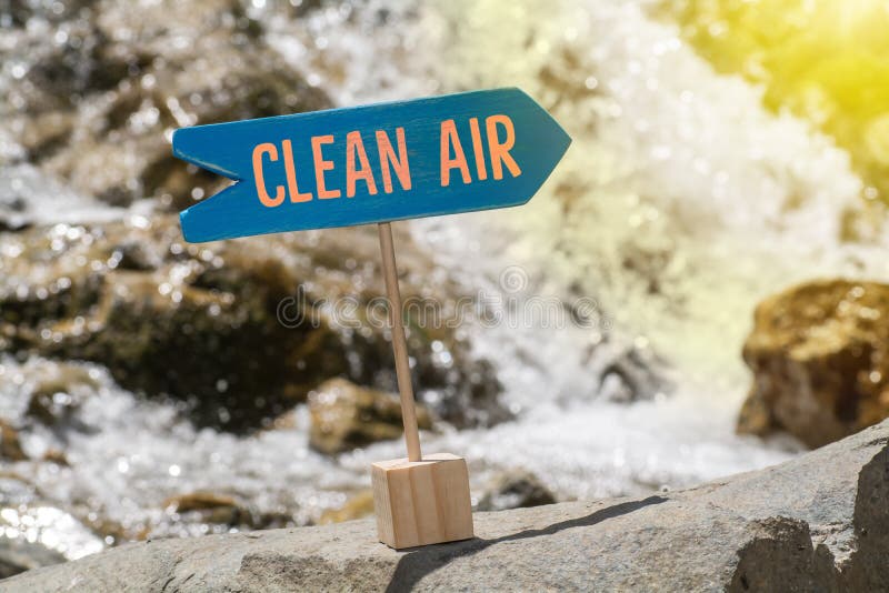 Clean air wooden sign board arrow on rock , river and sun shine background. Clean air wooden sign board arrow on rock , river and sun shine background