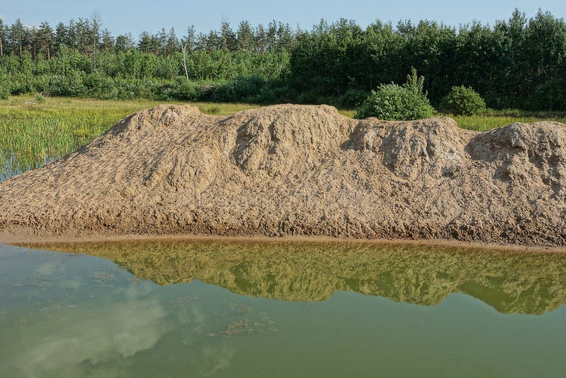 Część jeziora z zieloną wodą i kupą piasku brunatnego zdjęcie stock