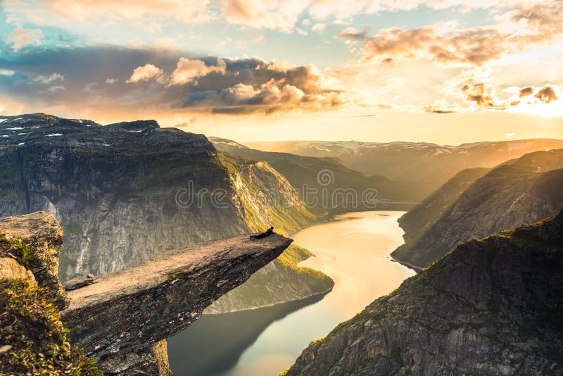 02/09-17, Trolltunga, Norway. A man is laying on the edge of trolltunga looking down. The drop is 700 m. 02/09-17, Trolltunga, Norway. A man is laying on the edge of trolltunga looking down. The drop is 700 m