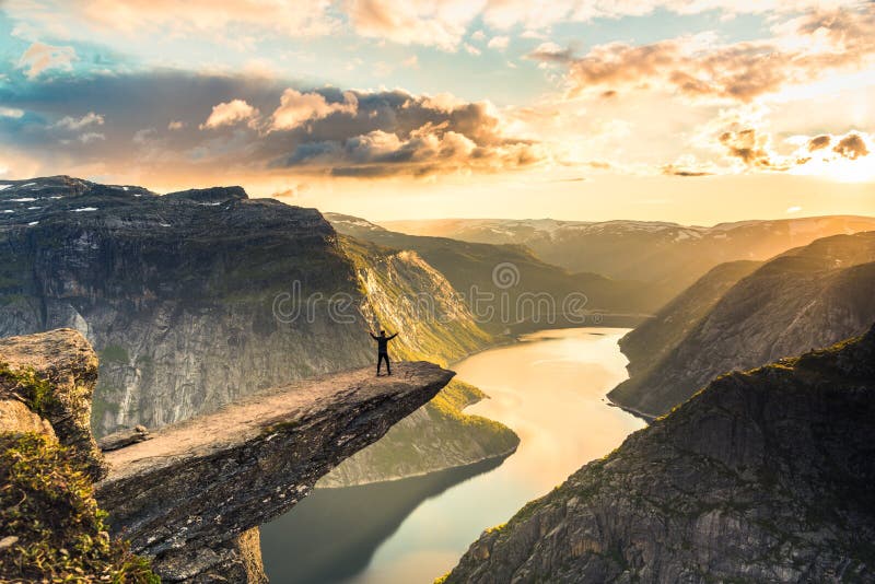 02/09-17, Trolltunga, Norway. A man is standing on the edge of trolltunga facing the sun. The drop down is 700 m. 02/09-17, Trolltunga, Norway. A man is standing on the edge of trolltunga facing the sun. The drop down is 700 m