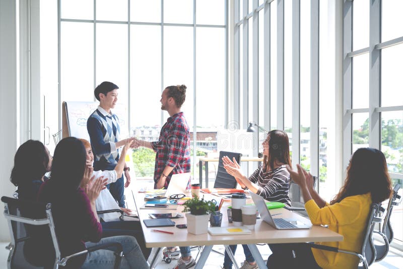 Cálida bienvenida feliz del equipo asiático creativo joven del diseño al nuevo empleado del cowork en el encuentro o el entrenami imagenes de archivo Cálida bienvenida feliz del equipo asiático creativo joven del diseño al nuevo empleado del cowork en el encuentro o el entrenami imagenes de archivo