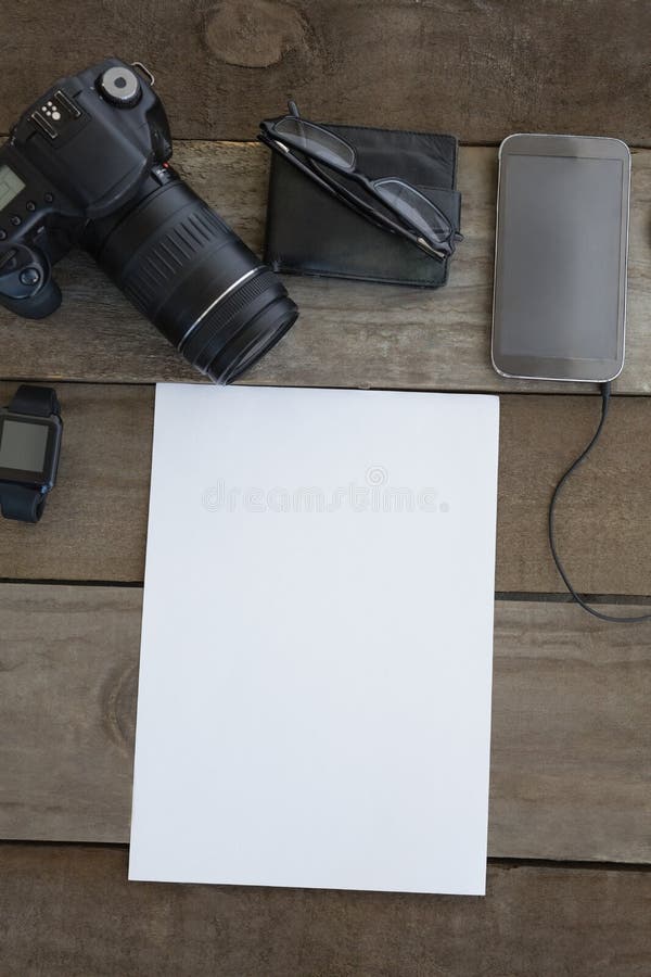 Cámara digital, cartera, gafas, smartwatch, teléfono móvil y documento en blanco sobre superficie de madera foto de archivo Cámara digital, cartera, gafas, smartwatch, teléfono móvil y documento en blanco sobre superficie de madera foto de archivo