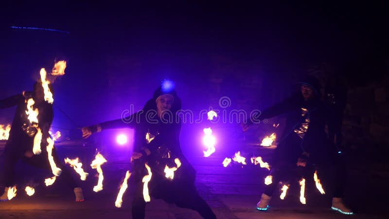 Cámara lenta de la demostración del fuego Los muchachos y las muchachas realizaron danzas con el fuego en la noche en la calle en