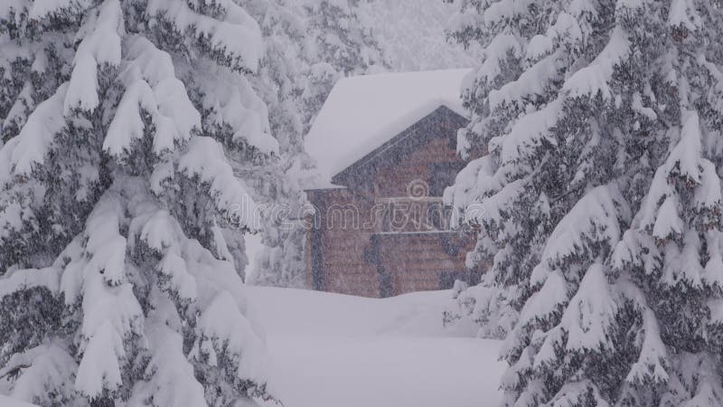 Cámara lenta sobre una casa rústica durante una tormenta de nieve en las montañas