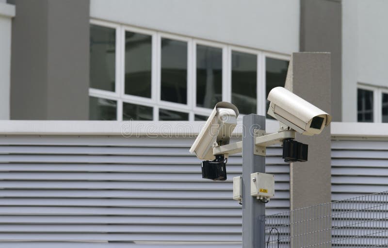 Two security cameras at the perimeter of a commercial office block. Two security cameras at the perimeter of a commercial office block