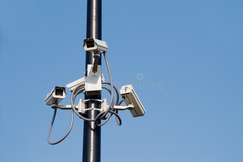 A series of security cameras on a pole. A series of security cameras on a pole.