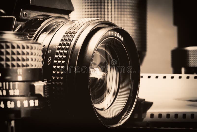 Black and white image of vintage professional cameras,lenses and a film roll. Black and white image of vintage professional cameras,lenses and a film roll