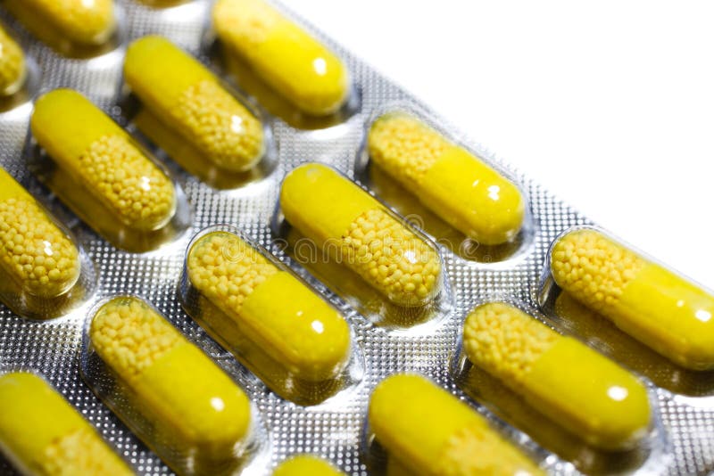 Cápsulas amarillas con la medicina amarilla de los gránulos en el detalle macro gris del paquete de ampolla de la píldora de la t imágenes de archivo libres de regalías Cápsulas amarillas con la medicina amarilla de los gránulos en el detalle macro gris del paquete de ampolla de la píldora de la t imágenes de archivo libres de regalías