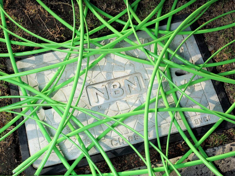 Câble à fibres optiques vert de NBN dans un désordre non structuré au-dessus d'un puits avec une couverture concrète de trou d'ho photo stock Câble à fibres optiques vert de NBN dans un désordre non structuré au-dessus d'un puits avec une couverture concrète de trou d'ho photo stock