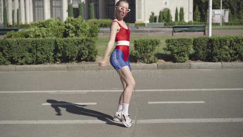 Câmera aproxima-se da alegre mulher magra caucasiana na dança retrodesportiva para música disco a partir de fita amarela vintage