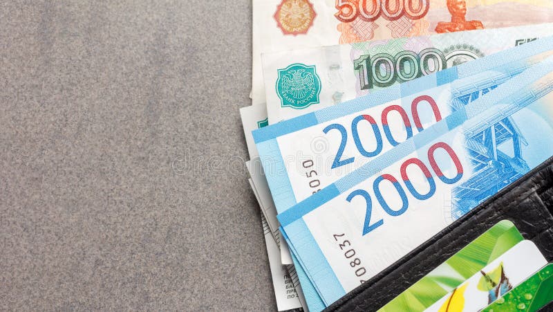 Cédulas novas do russo nas denominações de 1000, 2000 e 5000 rublos e cartões de crédito em um close-up de couro preto da bolsa imagens de stock Cédulas novas do russo nas denominações de 1000, 2000 e 5000 rublos e cartões de crédito em um close-up de couro preto da bolsa imagens de stock