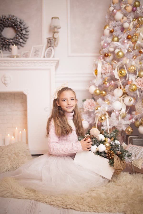 Célébration de Joyeux Noël Belle petite fille dans une robe se reposant près de l'arbre de Noël photo libre de droits Célébration de Joyeux Noël Belle petite fille dans une robe se reposant près de l'arbre de Noël photo libre de droits