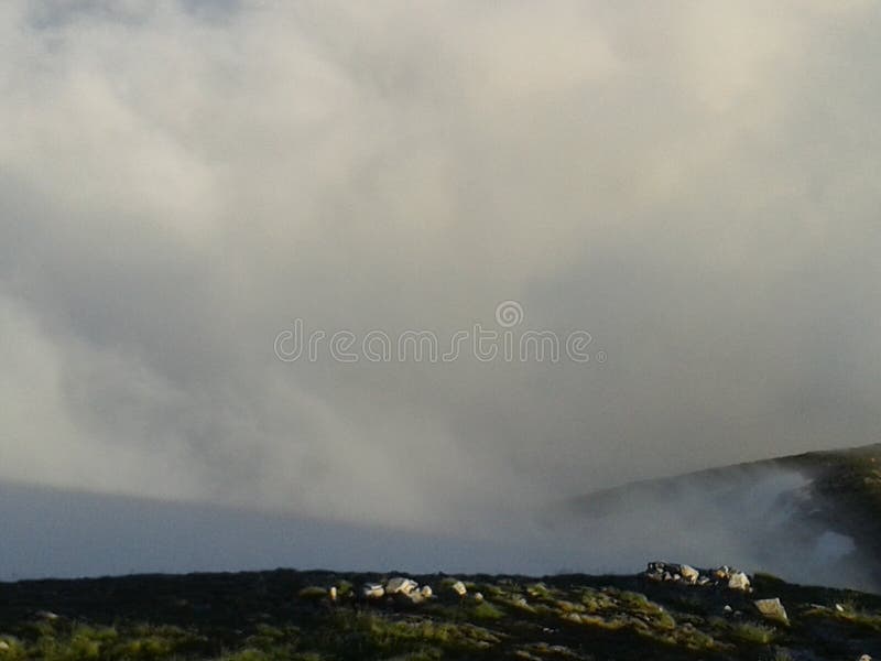 Céu nebuloso no por do sol sobre a parte superior da montanha foto de stock royalty free Céu nebuloso no por do sol sobre a parte superior da montanha foto de stock royalty free