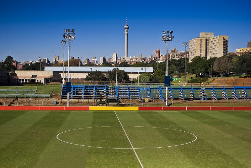 The empty center circle of a soccer pitch. Wider angle, showing the entire center circle, better suited for DPS. Visible in the background is one of Joburg's tallest & most prominent landmarks. All advertising hoardings have been blanked out, to facilitate easy branding for your own logo's. The empty center circle of a soccer pitch. Wider angle, showing the entire center circle, better suited for DPS. Visible in the background is one of Joburg's tallest & most prominent landmarks. All advertising hoardings have been blanked out, to facilitate easy branding for your own logo's