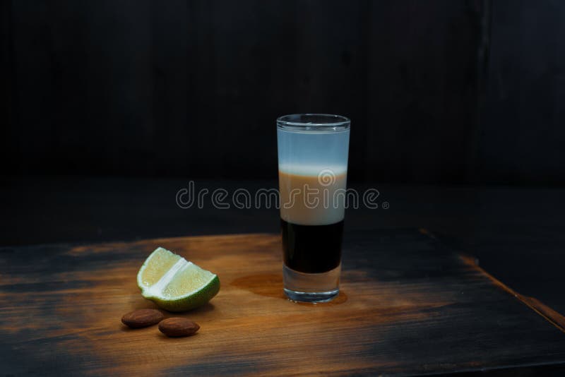 Cóctel alcohólico de la doble-capa con los soportes del jarabe de chocolate y del jarabe del coco en una tabla de madera del vint fotografía de archivo libre de regalías Cóctel alcohólico de la doble-capa con los soportes del jarabe de chocolate y del jarabe del coco en una tabla de madera del vint fotografía de archivo libre de regalías