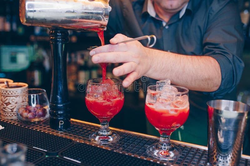 Cóctel de colada del rojo cereza del camarero usando bebida jugosa del alcohol dulce del tamiz en un contador de la barra Opinión foto de archivo libre de regalías Cóctel de colada del rojo cereza del camarero usando bebida jugosa del alcohol dulce del tamiz en un contador de la barra Opinión foto de archivo libre de regalías
